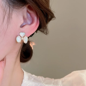 Close-up of elegant pearl-finish heart flower earrings worn by a model for a refined look