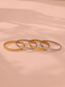 Close-up of 18K gold and silver stainless steel bangles with crystal inlay and sleek engraving