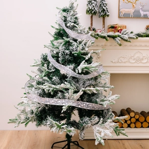 Detailed view of artificial Christmas tree with snow flocking and silver star ribbon