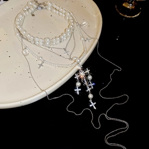 Detail of layered pearl necklace featuring rhinestone cross pendants on a ceramic plate