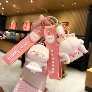Cute pink 3D pig keychain with silicone wristband and golden hardware held by hand