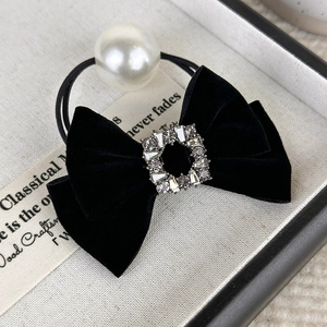Macro shot of vintage black velvet bow with rhinestone buckle and glossy pearl detail