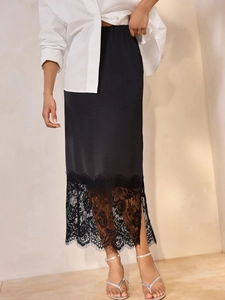 Detailed view of black satin midi skirt featuring delicate lace trim and side slit hem