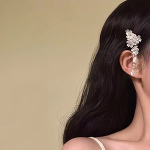 Macro view of a delicate white flower hair clip with elegant tassels worn by a model