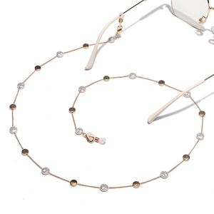 Detail of gold chain with irregular pearls and round sequins on white background