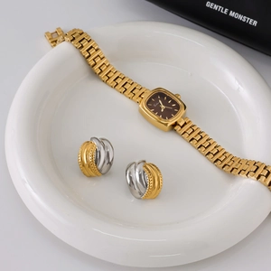Close-up of two-tone gold and silver twisted hoop earrings on white ceramic tray