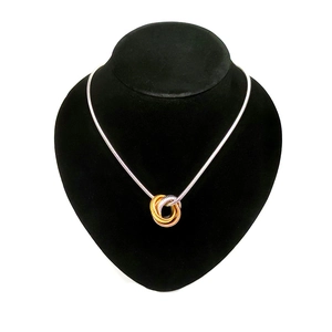 Three-tone interlocking ring pendant necklace on silver snake chain shown on a display