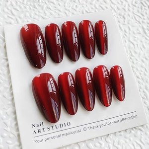 Faux ongles œil-de-chat bordeaux profonds de forme ovale sur carte de présentation