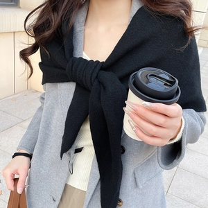 Détail d'un châle en maille noire porté sur un manteau en laine gris pour l'hiver