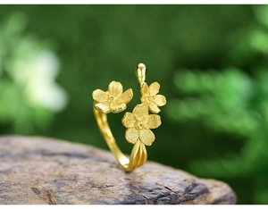 Macro view of gold flower ring with matte texture on natural stone with greenery
