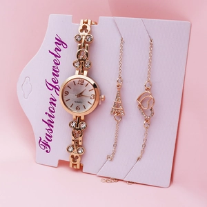 Close-up of gold quartz watch set with rhinestone clover, Eiffel Tower and heart bracelets