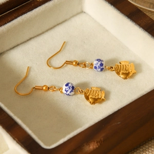 Élégantes boucles d'oreilles poisson doré avec perles en céramique dans une boîte en bois