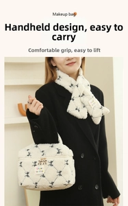 Detail of white faux shearling makeup bag featuring black bow patterns and gold zipper