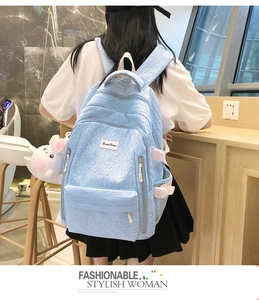 Gros plan du sac à dos bleu clair texturé avec son pendentif lapin blanc mignon