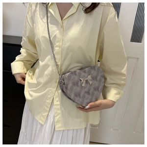 Chic grey heart-shaped PU crossbody bag with silver chain strap and bow detail on a model
