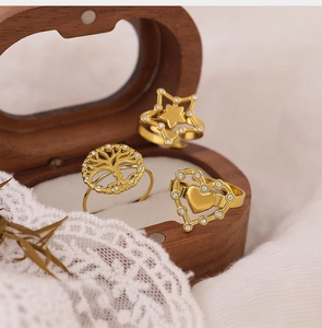 Close-up of golden zircon tree of life star and heart rings in a wooden jewelry box