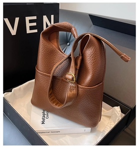 Détail de la texture cuir grainé marron caramel et boucle dorée du sac seau chic