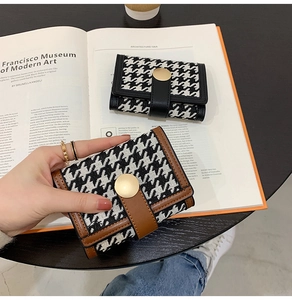 Detail of houndstooth wallet texture with vintage gold buckle and faux leather trim