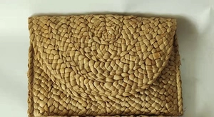 Detailed view of the woven corn husk material and envelope closure on the handbag