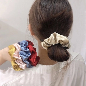 Close-up of velvet floral scrunchies in multiple colors worn on hair and wrist