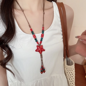 Detail of bohemian red ceramic starfish pendant on braided cord with colorful beads