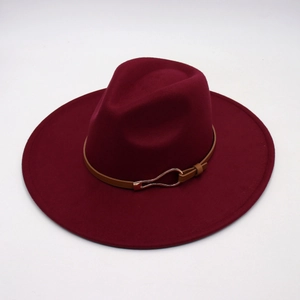 Detail of burgundy felt fedora hat featuring a brown leather strap and gold horseshoe buckle