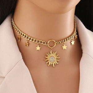 Collier en acier doré avec pendentifs soleil et étoiles porté sur fond rose clair doux