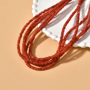 Macro shot of 4mm orange flat round shell beads on a white scalloped dish for DIY jewelry