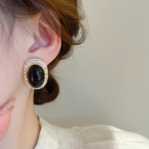 Close-up of vintage oval black stone earring with sparkling crystal border on model