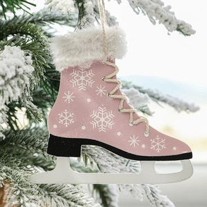 Pink wooden ice skate Christmas ornament with white snowflakes hanging on a snowy tree