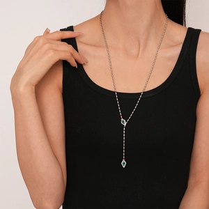 Détail du collier en Y argenté avec pendentifs émeraude et accents de cristaux blancs