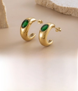 Detail of C-shaped gold-plated stainless steel earrings with oval green zircon inlay