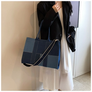 Detail of blue denim patchwork tote bag with contrast stitching and shoulder strap