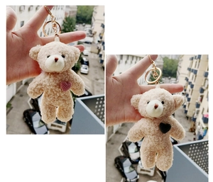 Detail of plush beige teddy bear keychains with red heart embroidery and gold rings