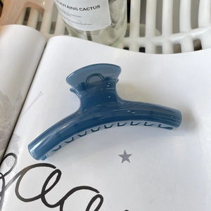 Navy blue resin shark hair clip with translucent finish on a stylish background