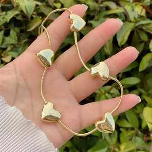Detail of 18k gold plated snake chain with five polished heart pendants held in hand