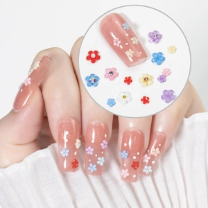 Macro shot of 3D multi-colored resin flowers and beads on clear manicure false nails