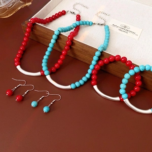 Ethnic turquoise beaded jewelry set including necklaces and earrings on a vintage wooden tray