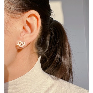Eleganti orecchini a lobo minimalisti a nodo in smalto bianco crema su modella