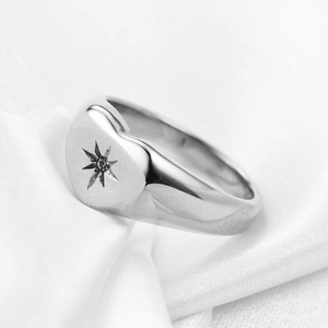 Macro shot of 18K gold heart ring with star engraving on white satin background