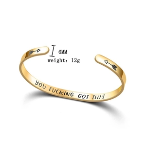 Detail view of gold titanium steel bangle showing engraved motivational inner text and arrows
