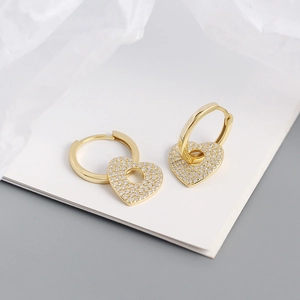 Close-up of gold heart drop earrings with pave zircons and circular cutout details