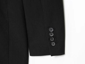 Détail des poignets de veste noire avec quatre boutons assortis sur tissu de qualité