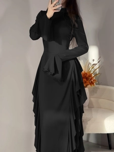 Détail d'une robe noire élégante à manches longues avec poignets et ourlet à volants