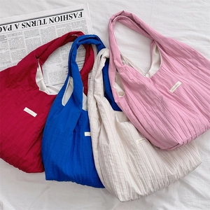Close-up of minimalist pleated tote bags in red, blue, beige, and pink colors