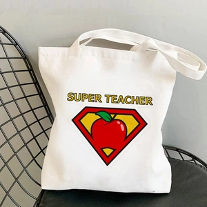 White canvas tote bag with Super Teacher heart print placed on a black chair