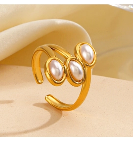 Detailed view of an adjustable gold pearl ring with three white pearls on a silk background