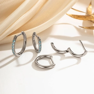 Titanium hoop earrings with blue cubic zirconia on a natural decorative fabric