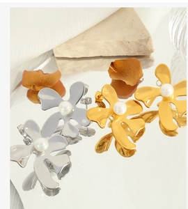 Gros plan de boucles d'oreilles fleurs et perles en or et argent sur socle miroir