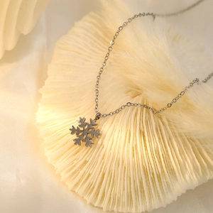 Detail of silver snowflake pendant necklace on white coral stand with soft lighting